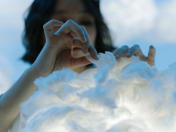 Person meditating peacefully with soft blue light in the background.